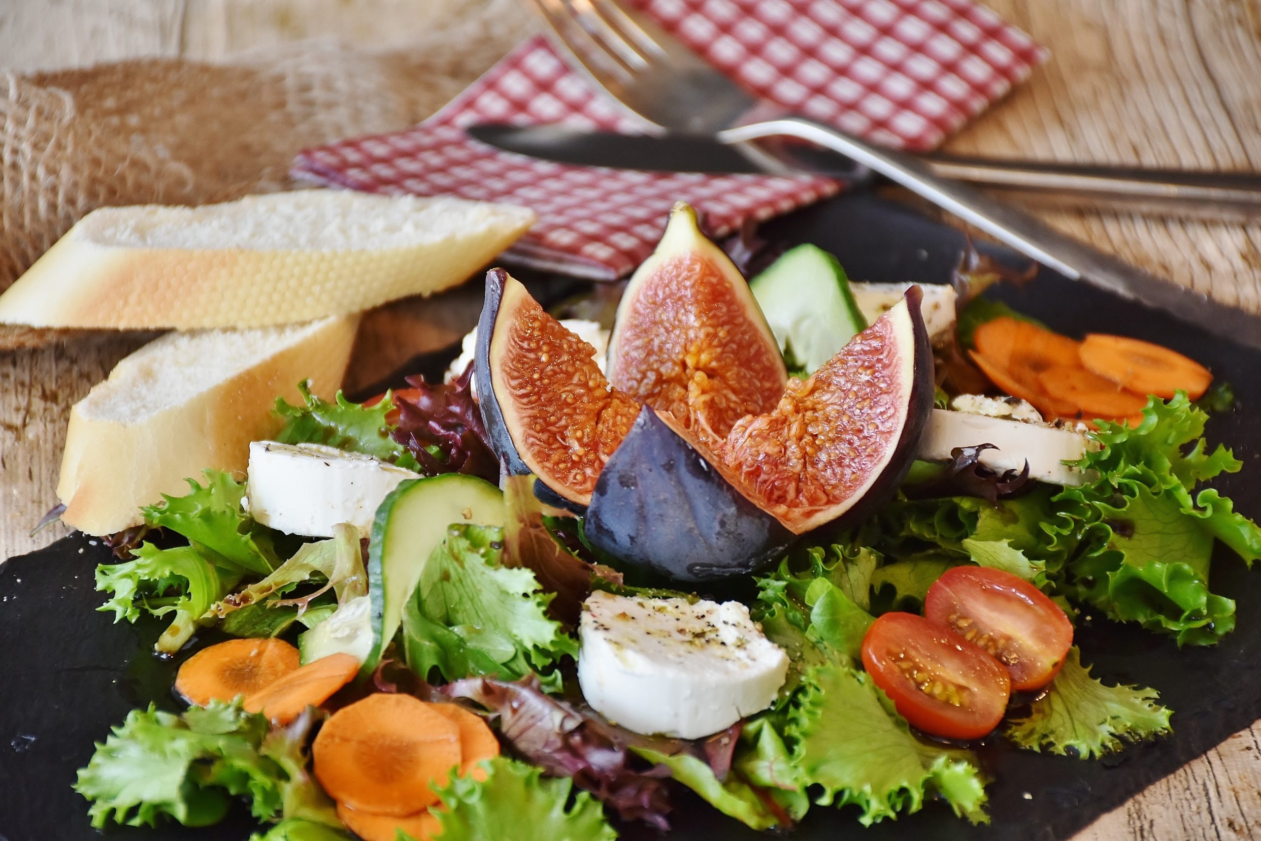 appetizer dish containing a fig, tomatoes, cheese and lettuce