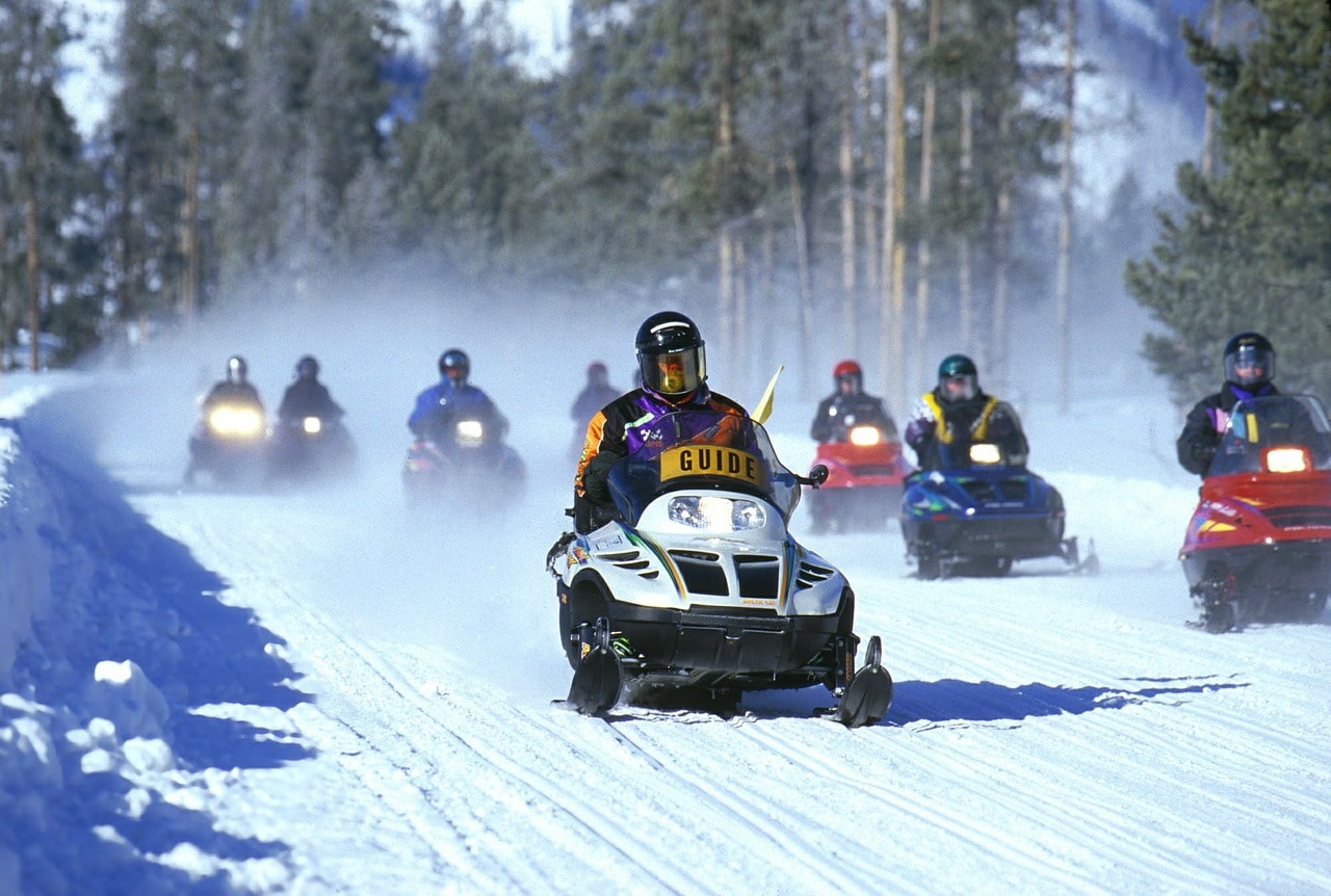 Many individuals riding snowmobiles