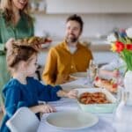 family sitting around a table celebrating Easter with a brunch at home - bright photo with family time