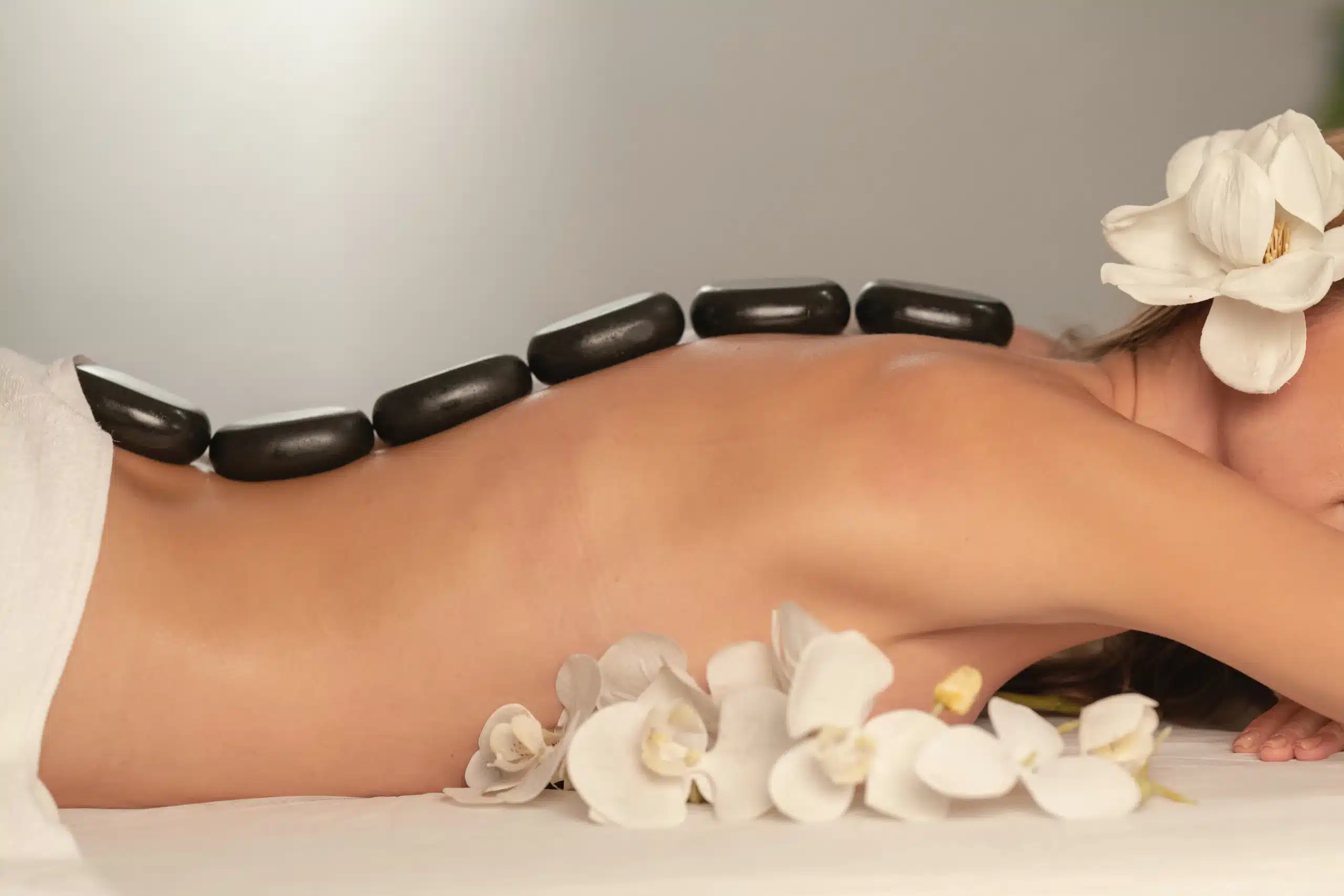 woman lying on stomach with spa hot stones along her back