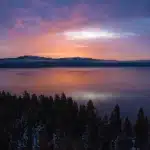 sunset view of lake tahoe with snowy mountains in the distance