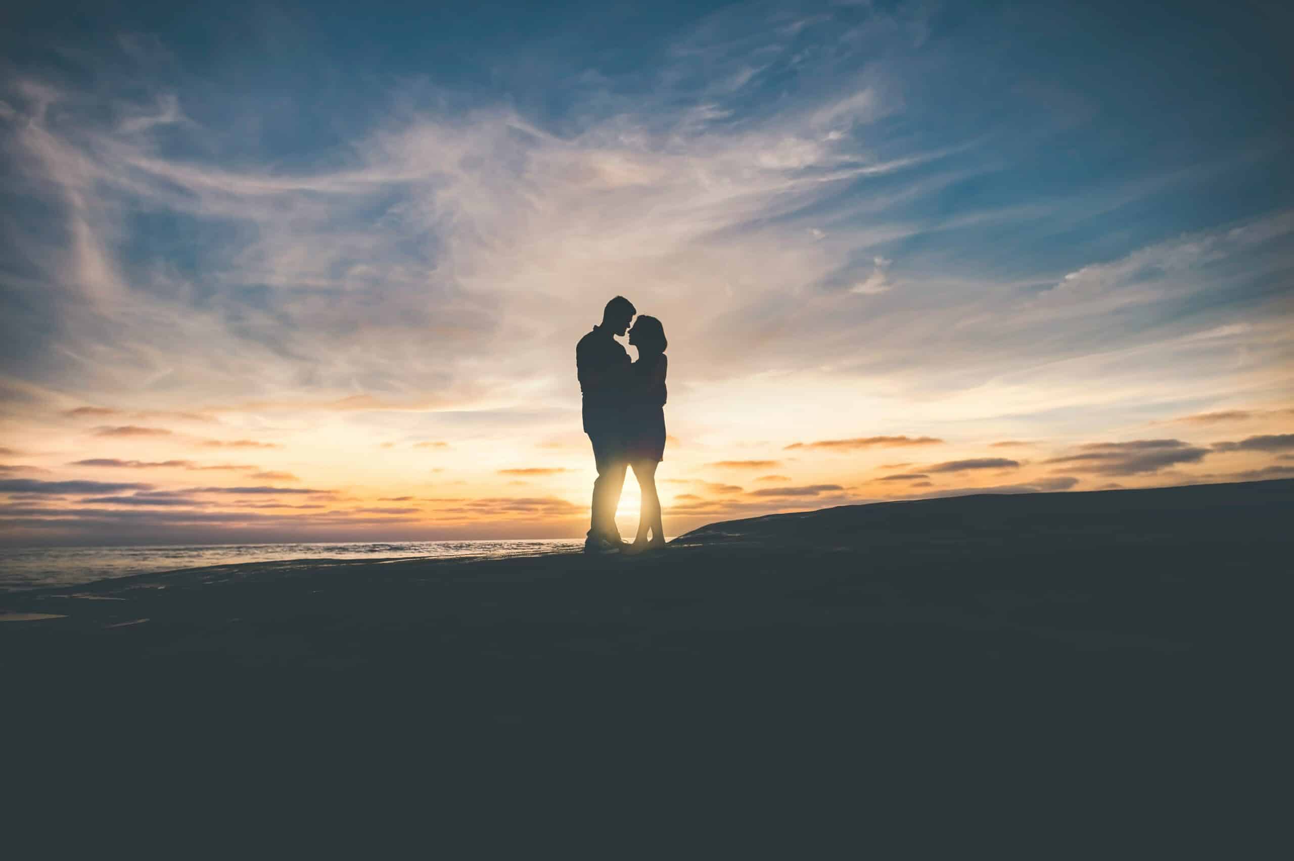 man and woman hugging at sunset