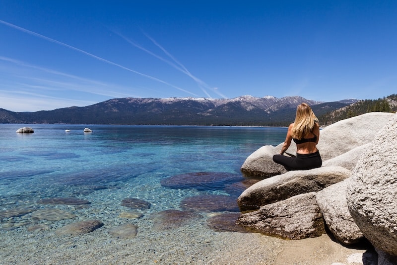 Woman sitting on a boulder on the shores of Lake Tahoe in the summer - summer Lake Tahoe