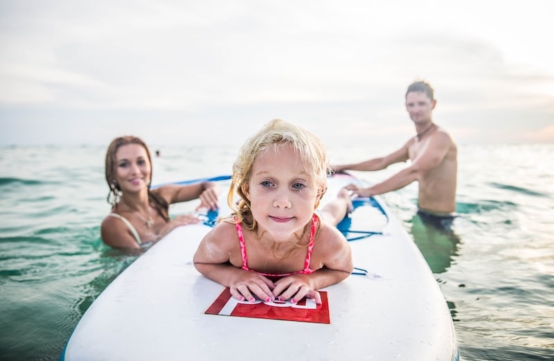 man and woman helping a child on a paddleboard