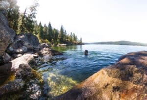 man swimming in the lake near rocks