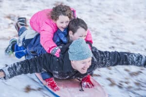 father with two kids sledding