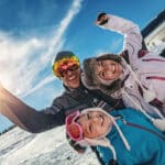 family of three enjoying a sunny day on a ski mountain