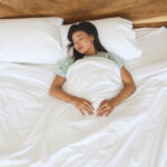 Peaceful Sleep Of A Woman Relaxing In A Cozy Bed Surrounded By Soft White Sheets And Natural Light, Creating A Serene And Tranquil Atmosphere For Rest And Rejuvenation.