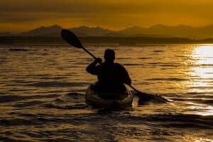 silhouette of a person paddling a kayak in the sunset