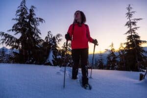 Adventurous Girl Snowshoeing in the snow on top of a mountain