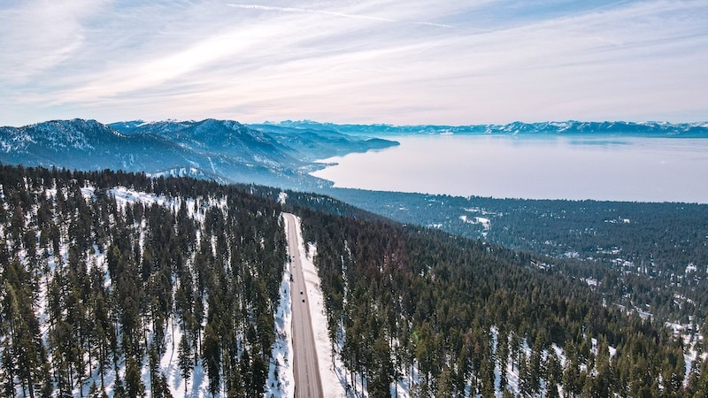 Aerial of Lake Tahoe in the Sierra Nevada of the United States next to a snow-covered sparse forest