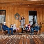 Attractive mother with her four kids on the terrace of a wooden house in winter day.