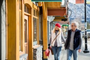 couple-in-warm-clothing-walking-along-storefront