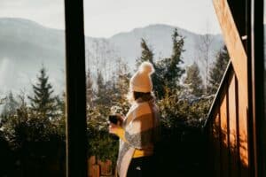 woman enjoying hot cup of tea on terrace in winter mountains ski holiday lodging